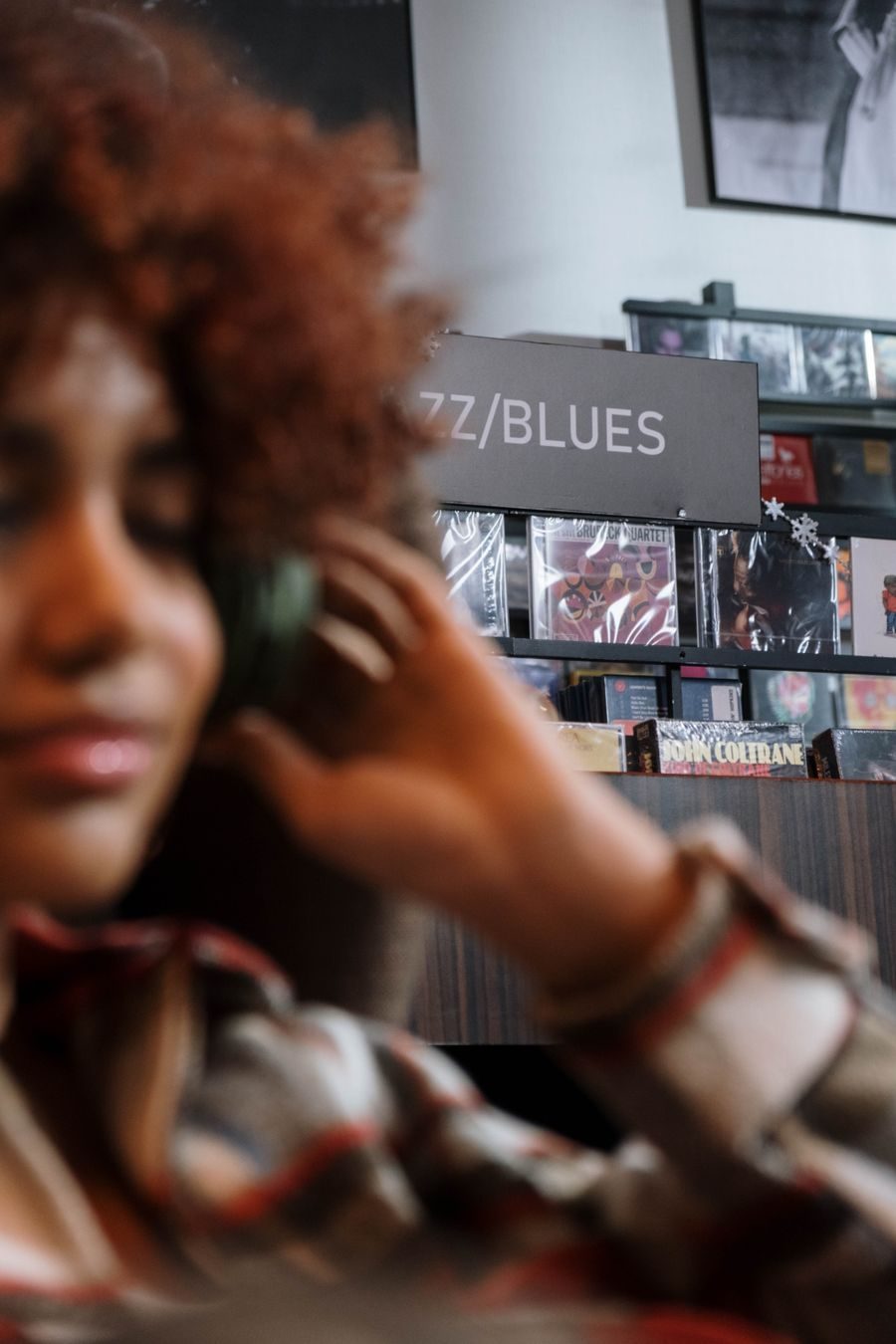Browsing shelves with headphones on, ready to listen