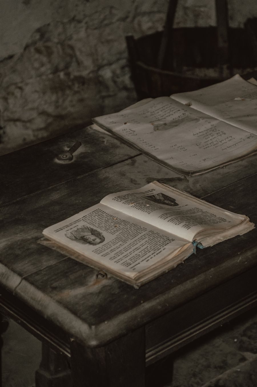 Old hardcover books open on a dark wooden table