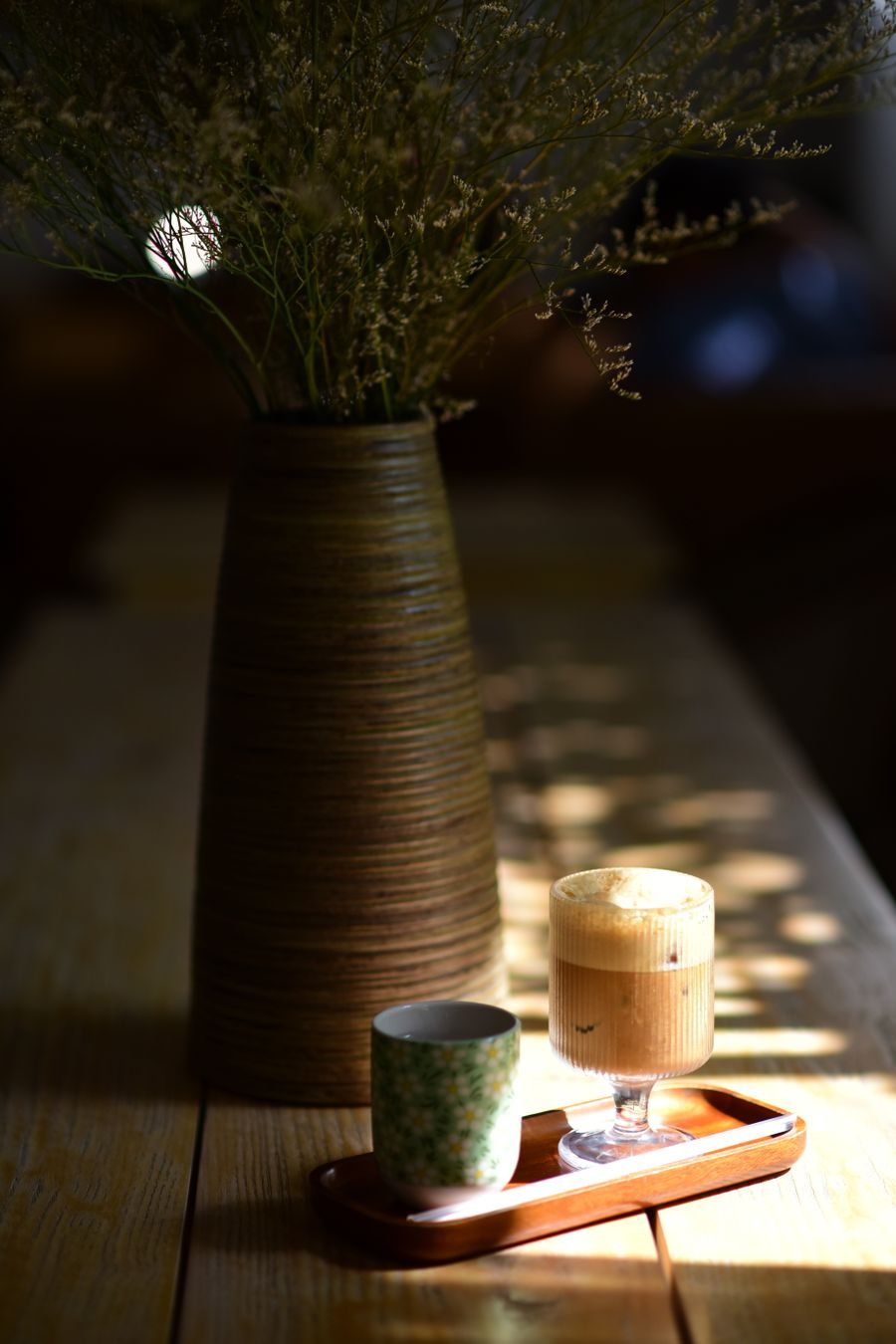 Coffee and a candle on a wooden tray in soft light