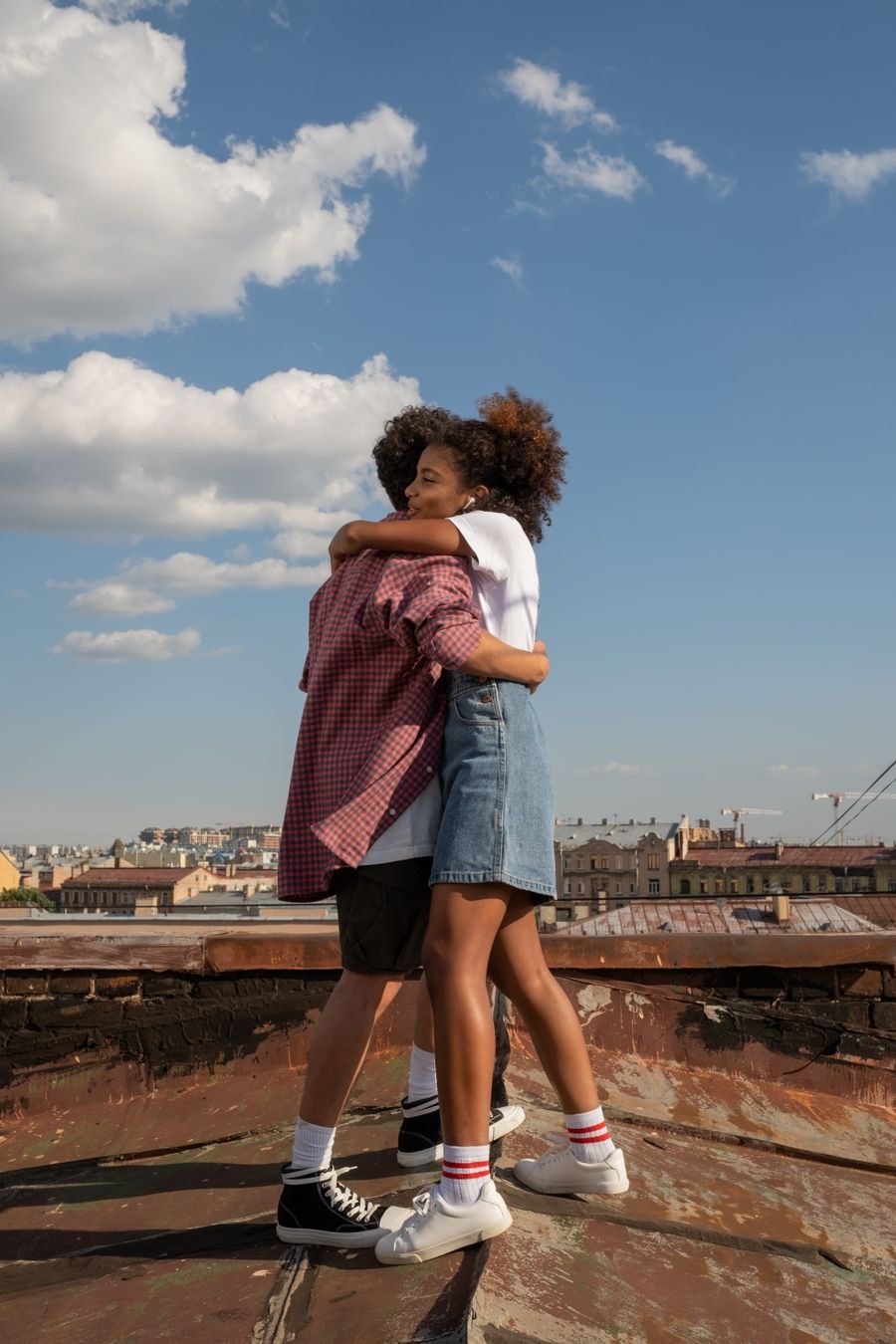 Two teenagers hugging outdoors on a sunny day