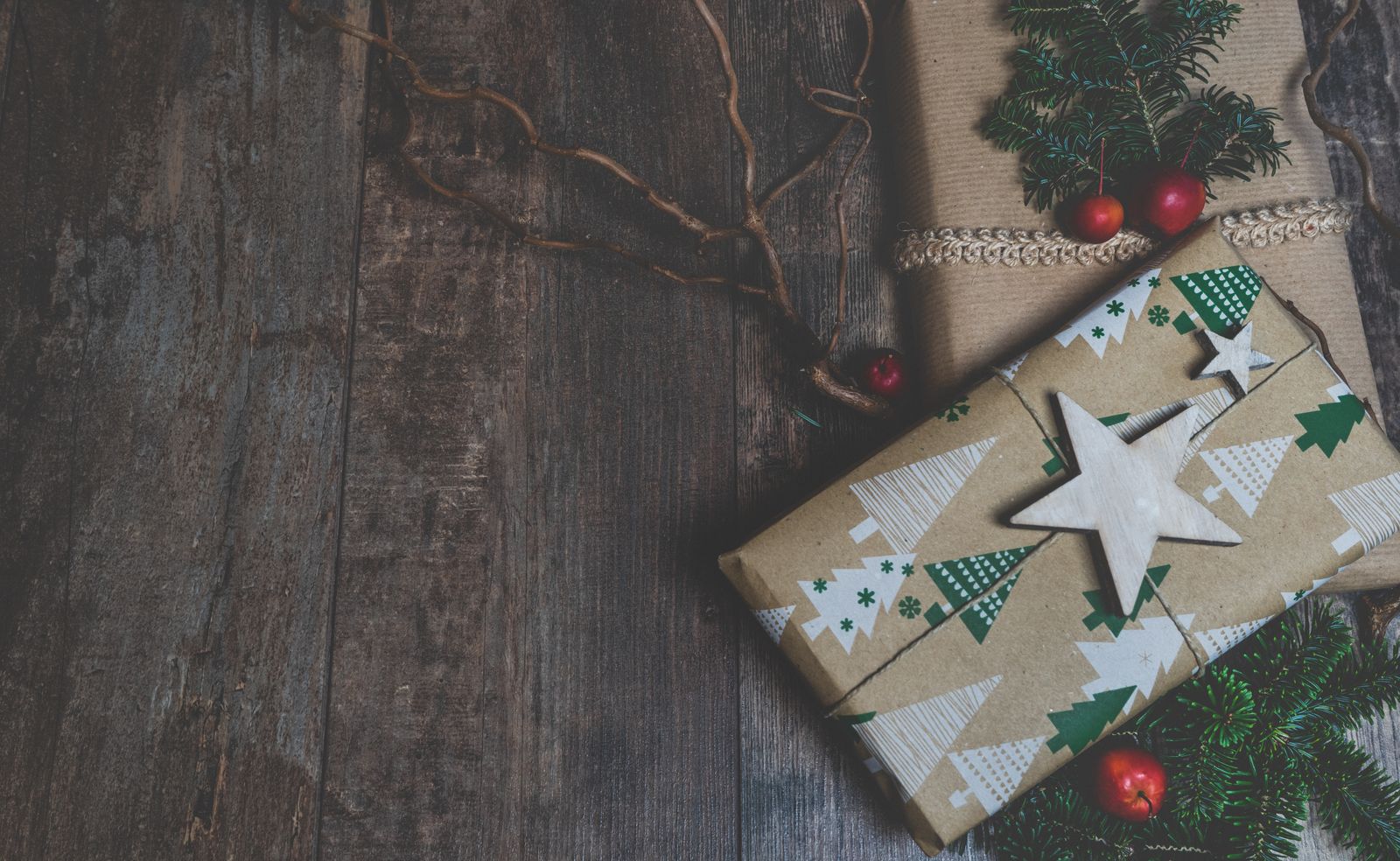 Kraft-wrapped Christmas gifts with pine sprigs on a wooden table